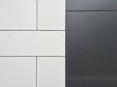 Alternatif açık gri ve koyu gri metal panelleri geometrik desenli düzenlenmiş modern bir duvara yakın plan, her panel endüstriyel görünüm için görünür perçinlerle korunuyor..