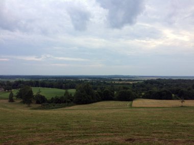 Bulutlu kırsal alan, hareketli tarlalar, uzak ormanlar, ve uçsuz bucaksız bulutlu gökyüzü, doğa ve sükunet temaları için mükemmel..