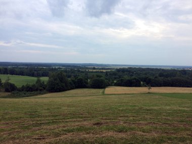 Bulutlu kırsal alan, hareketli tarlalar, uzak ormanlar, ve uçsuz bucaksız bulutlu gökyüzü, doğa ve sükunet temaları için mükemmel..