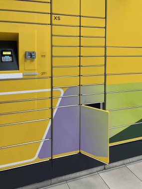 Açık ekran arayüzü, dokunmatik ekran arayüzü ve renkli geometrik tasarımı olan, modern self-servis paketini temsil eden parlak sarı paket dolabı..