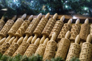 Üzerinde şenlik ve çiçek desenleri işlenmiş ahşap raptiyeler var. Sergi yeşil ve yumuşak dekoratif ışıklarla çerçevelenmiş, bu da bir pazar veya mevsimlik fuar ortamı izlenimi uyandırıyor.