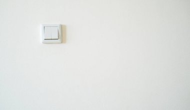 Sol tarafında ışık düğmesi olan en az beyaz desenli duvar. Yumuşak doğal ışık yüzeyde ince gölgeler ve gölgeler yaratır. Arkaplan kullanımı için uygun geniş negatif alana sahip temiz, basit bileşim.