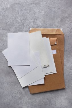 Beyaz kağıtlar, beton arka planda el işi zarflar. Metin ve çizimler için yer.