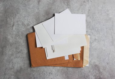 Beyaz kağıtlar, beton arka planda el işi zarflar. Metin ve çizimler için yer.