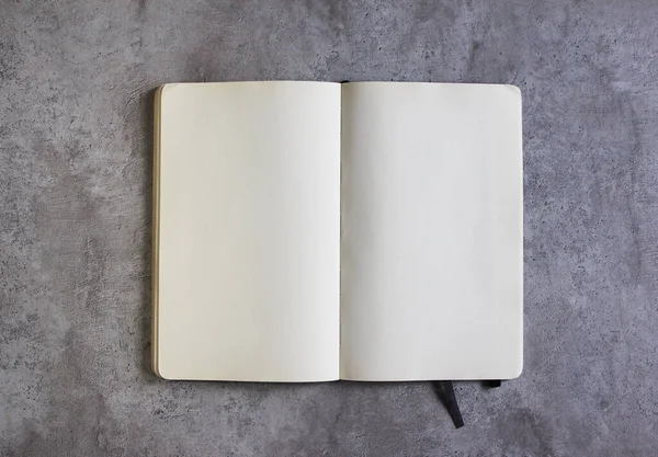 Çimento arka planında açık bir defter. Metin için boş sayfaları olan not defteri.