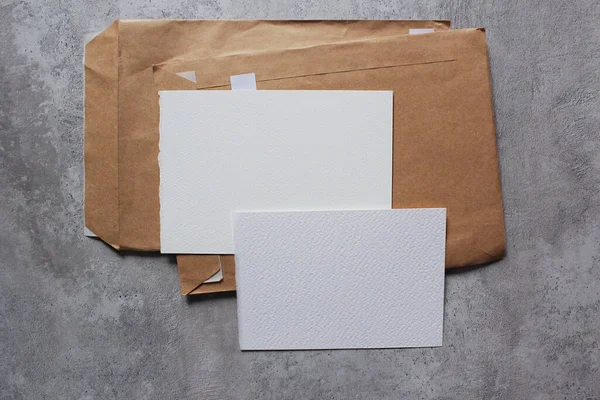Beyaz kağıtlar, beton arka planda el işi zarflar. Metin ve çizimler için yer.