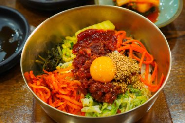 Geleneksel Kore pirinç kasesinde çiğ biftek ve yumurta sarısı ile Jeonju Bibimbap 'ın renkli bileşenleri