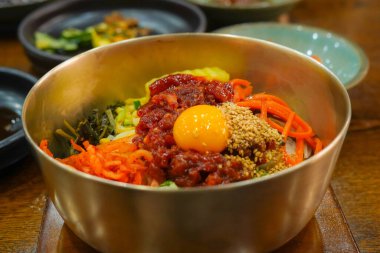 Geleneksel Kore pirinç kasesinde çiğ biftek ve yumurta sarısı ile Jeonju Bibimbap 'ın renkli bileşenleri