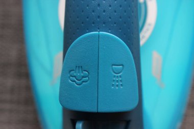 Ev ütüsünün makro buhar ve sprey kontrol düğmelerini kapatın. Dokunulabilir mavi plastik ve berrak simgeler.