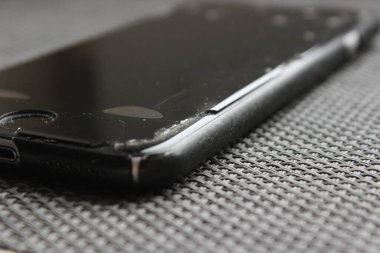 Kaldırılmış ekran ve yontulmuş çerçeveli yıpranmış bir akıllı telefonun yakın çekimi. Çarpışmadan sonra görünür aşınma, tamir ve bakım teması.