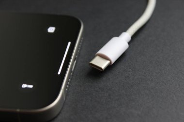 USB-C kablosunun karanlık bir yüzeyde modern bir akıllı telefonun yanında, şarj etme konsepti.