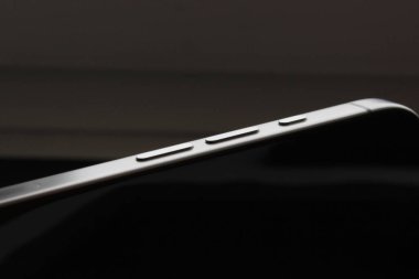 Modern bir metal kenarlı akıllı telefondaki koyu arkaplana karşı hacim düğmelerinin temiz makrosu.