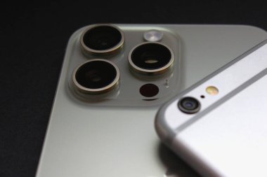 iPhone 6 'nın iPhone 15 Pro Max üzerindeki yakın görüntüsü, tek ve üçlü kameraları vurguluyor. Sadece editör kullanımı.