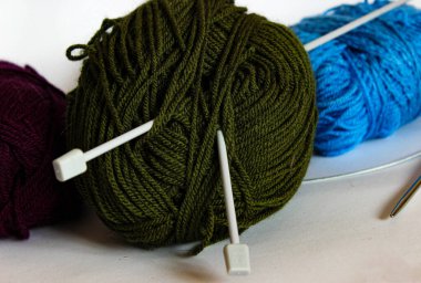 Beyaz düz iğneli zeytin yumağı arka planda mavi ve mor iplikler. DIY ve hobi görselleri için klasik örgü sahnesi.