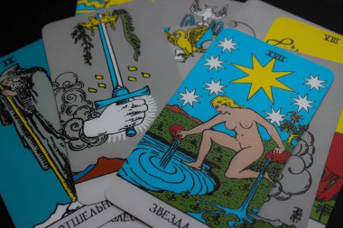Yıldız kartının detaylı yakın plan çekimleri ve dağınık tarot kartları. Karanlık bir arka planda sığ alan derinliği. Rehberlik, umut ve kehanet üzerine makaleler için ideal.