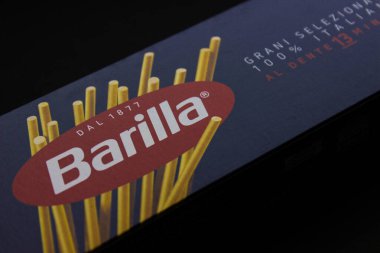 Etikette resmedilmemiş spagetti ile Barilla makarna paketinin yakın çekimi. Koyu bir arka planda sunulan tanınabilir yiyecek markası.