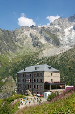 Alplerdeki Chamonix 'in yukarısındaki Mer de Glace buzulunun yanındaki dağ otelinde güneşli bir yaz günü, bir grup turist dağ yürüyüşünden önce ısınıyor.