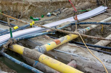 Yeraltı altyapı kurulumu sırasında kazılmış bir siperde birden fazla büyük elektrik borusu ve kablo kanalı geçiyor..