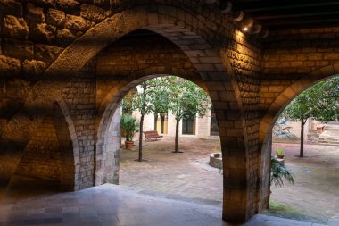 Büyük taş kemerlerin iç manzarası seramikleri, ağaçları ve bankları olan sessiz bir avluya açılıyor..