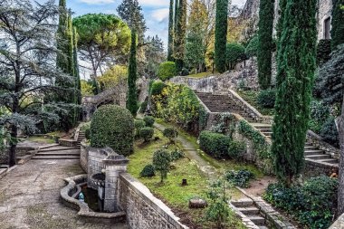 Jardins de La Francesa, Girona, İspanya 'daki tarihi teras bahçeleri taştan merdivenlerden taşar. Selvi ağaçları, yontulmuş çalılar ve Akdeniz bitkileri eski bir taş çeşmenin etrafını sararak yıpranmış duvarlar arasında dingin bir vaha oluşturuyor.