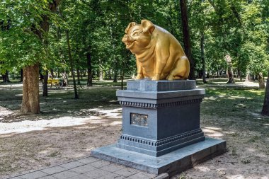 Taras Shevchenko Şehir Parkı 'ndaki taş heykel heykeli, Romny, Sumy bölgesinde yeşil ağaçlar ve yaz yapraklarıyla çevrili. Dekoratif bronz heykel park ziyaretçileri için popüler bir dönüm noktası olarak hizmet vermektedir. Romny, Ukrayna - 29 Haziran 2024