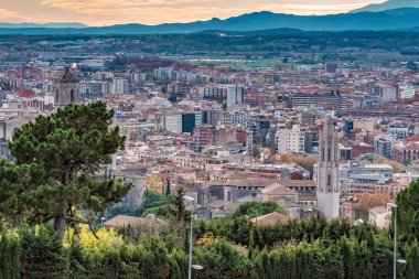 Katalonya, İspanya 'daki Girona şehrinin panoramik hava manzarası, tarihi katedral, kentsel mimari ve Pyrenees dağları arka planda. Şehir manzarasında modern bölgelerle çevrili ortaçağ eski kasaba binaları sergileniyor.