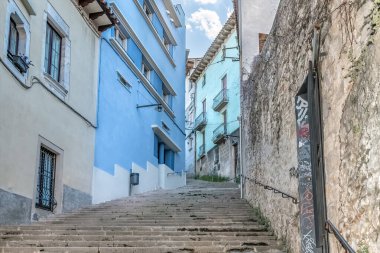 Carrer de la Llebre caddesindeki dik taş merdiven Girona 'nın tarihi bölgesinde renkli binalar arasında dönüyor. Mavi ve nane rengi cepheler, bu dar yol boyunca uzanan antik taş duvarlarla tezat oluşturuyor. Girona, İspanya - 28 Kasım 2021