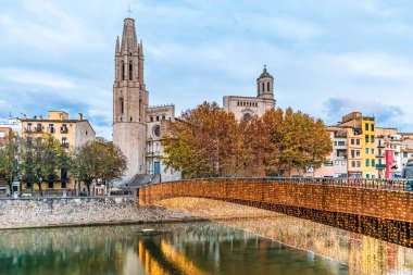 Pont de Sant Feliu köprüsünü alacakaranlıkta Onyar Nehri 'ne yansıyan Noel ışıklarıyla aydınlatmış, Sant Feliu Bazilikası ve arka planda renkli evler bulunmuştur. İspanya 'nın tarihi Girona şehrinde şenlikli kış sahnesi