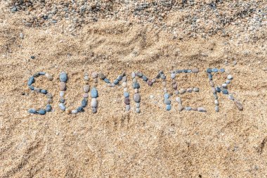 Güneşli bir kumsaldaki doğal deniz çakıl taşlarından elde üretilen SUMMER sözcüğünün doğrudan üst görüntüsü. Kopya uzayı ile yaratıcı düz kompozisyon. Mevsimlik seyahat ve tatil pazarlaması için ideal.