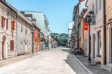 Cetinye 'deki Njegoseva yaya caddesinin geniş bir manzarasında tarihi mimari ve açık hava kafeleri yer alıyor. Boş yürüyüş yolu şehir merkezindeki huzurlu sabah atmosferini vurguluyor. Cetinje, Karadağ - 20 Haziran 2021