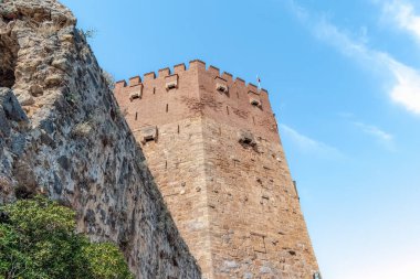 Türkiye 'nin Alanya kentindeki tarihi Kızıl Kule' nin (Kizil Kule) alçak açılı görüntüsü. Eski taş ustası ve tuğla deseni açık mavi gökyüzüne karşı seyahat tasarımı için fotokopi alanı