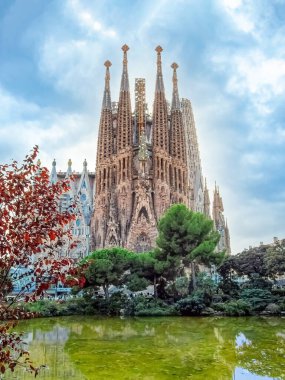 Sagrada Familia gölete yansıdı. Suyu çevreleyen yeşil ağaçlar. Barselona, İspanya - 10 Ekim 2018