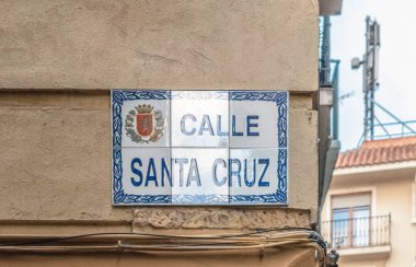 Sarı bir duvar üzerinde Calle Santa Cruz için geleneksel seramik karo tabela. Şehir arması olan otantik dekoratif azulejo plaketi. Zaragoza, İspanya - 29 Kasım 2021