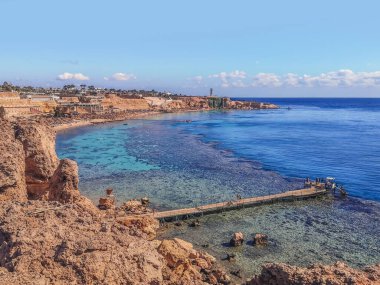 Mısır 'ın Sharm El Sheikh kentindeki Kızıl Deniz' de mercan resifi olan bir uçurumdan sahile bakın. Tropikal bir tatil köyünün güzel egzotik manzarası