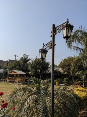 Şatafatlı klasik çift lamba direği gururla duruyor güneşli bir halk parkında kırsal ahşap bir çardağı olan
