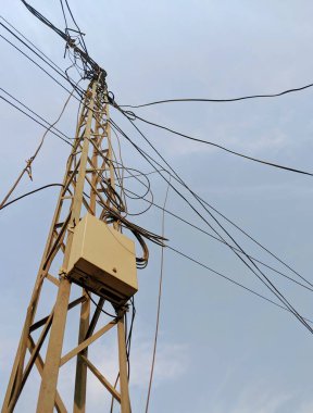 Çelik kafes direğinin dağınık kablolu ve kutulu düşük açılı fotoğrafı.