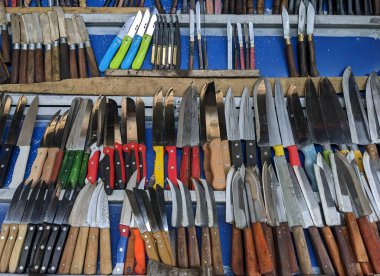 Mavi arka planda çeşitli çelik bıçaklar, ahşap ve renkli plastik saplar.