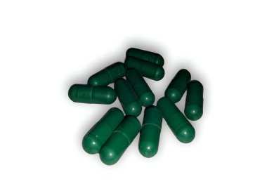 Koyu yeşil ilaç kapsülleri sade beyaz arka plan stüdyo fotoğrafçılığına saçılmış.