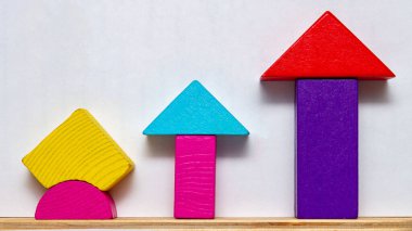 Çok renkli geometrik tahta bloklar, büyümeyi, ilerlemeyi, gelişmeyi, yönü ve gelişmeyi simgeleyen yukarı dönük oklar oluştururlar. Ticari büyüme kavramlarını keşfetmek, çocuklara öğretmek, yaratıcılık ve yükselen eğilimler için ideal.