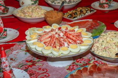 Haşlanmış yumurta, yengeç bacağı, geleneksel salata ve çeşitli parti yemekleri olan bir şenlik masası. Tatiller, kutlamalar, aile yemekleri ve aşçılık etkinlikleri için mükemmel..