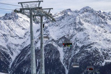 Sandalye, kayakçıları karla kaplı bir dağlık arazide taşıyor. Kış sporu, kayak merkezi, dağ yolculuğu ve açık hava macerası konsepti.