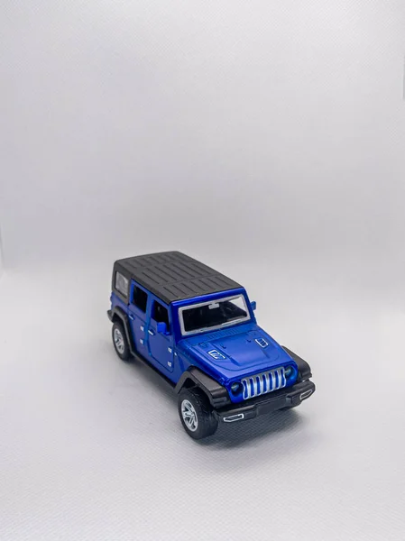 Siyah çatılı mavi oyuncak SUV, beyaz arka planda detaylı aynalar, saplar ve ızgara..