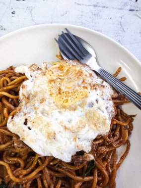 Görüntü, çok sayıda Güneydoğu Asya ve Doğu Asya yemeği için yaygın bir sunum olan kızarmış yumurtalı bir tabak erişteyi gösteriyor..