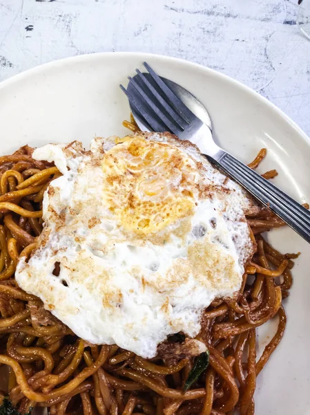 Görüntü, çok sayıda Güneydoğu Asya ve Doğu Asya yemeği için yaygın bir sunum olan kızarmış yumurtalı bir tabak erişteyi gösteriyor..