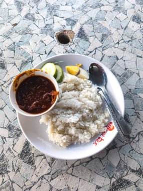 Bir tabak Nasi Lemak ile hindistan cevizi pilavı, baharatlı sambal, salatalık ve mozaik masasında yumurta..