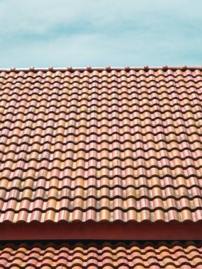 Terracotta çatı kiremitleri, soluk mavi gökyüzünün altında ritmik bir desen oluşturur..