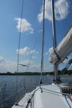 Güneşli bir yaz gününde güzel beyaz bir yat nehir boyunca yol alır.