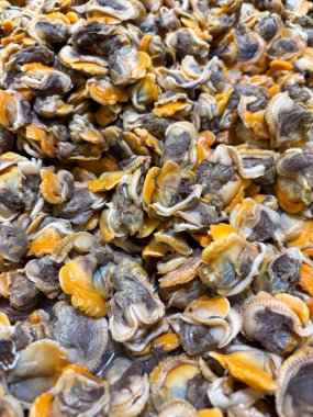 Büyük miktarda taze, kabuğu soyulmuş midyelerin yakın çekim görüntüsü karakteristik turuncu ve gri et dokusunu pişirmeye hazır hale getiriyor.