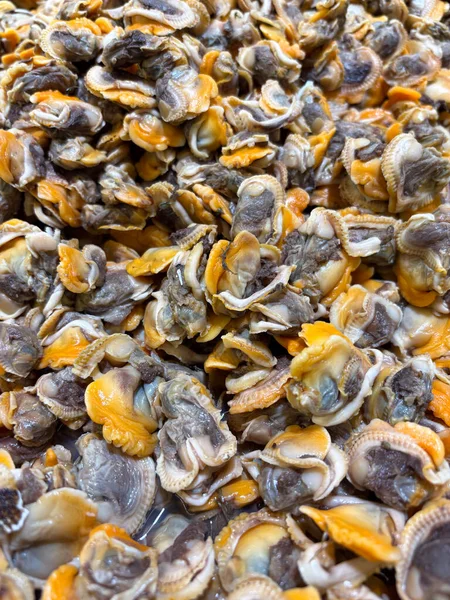 Büyük miktarda taze, kabuğu soyulmuş midyelerin yakın çekim görüntüsü karakteristik turuncu ve gri et dokusunu pişirmeye hazır hale getiriyor.