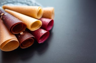Masanın üzerinde renkli meyve ruloları var. Meyvelerin doğal tatlısı. Meyve pastil çarşafları.